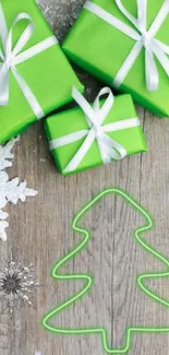 Green gifts and tree outline with snowflakes on wooden surface.