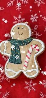 Gingerbread man with scarf and candy cane on red snowflake background.