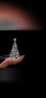 Hand holding a sparkling Christmas tree on a black mobile phone wallpaper.