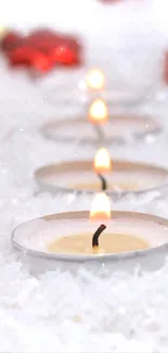 Festive mobile wallpaper of red ornaments and candles on a snowy background.