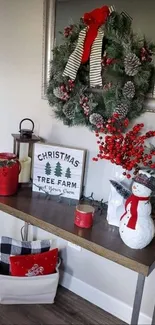 Festive holiday decor with wreath and snowman on console table.