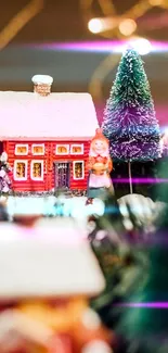 Festive miniature scene with red house, evergreens, and holiday lights.