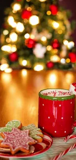 Festive red mug with Christmas cookies in front of a lit holiday tree.