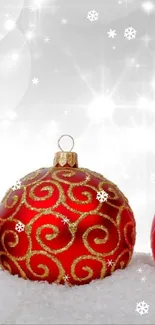 Festive red Christmas ornaments on snow with sparkling lights.