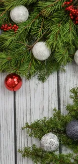 Festive wallpaper with pine branches, red berries, silver and red ornaments on white wood.