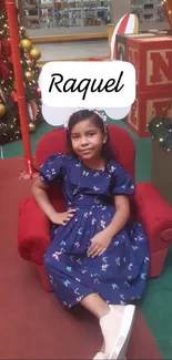 Girl in blue dress sitting in festive holiday setting.