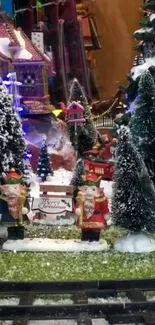 Snowy holiday village scene with Christmas trees and festive figures.