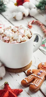 White mug with hot cocoa and marshmallows, surrounded by Christmas decor.