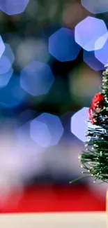 Miniature Christmas tree with red decorations and bokeh lights in the background.