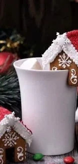 Festive gingerbread houses on a mug with holiday decor.