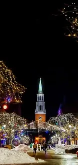 A brightly lit festive city street with a towering church on a winter night.