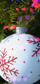 Christmas ornament with snowflake on evergreen branch, colorful hearts.