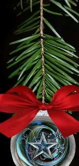 Christmas ornament with red ribbon and pine branch on black background.