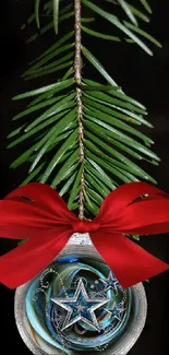 Festive ornament with red ribbon on pine branch against black background.