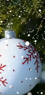 Festive Christmas ornament on pine tree with snowflakes.