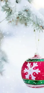 Red Christmas ornament with snow on a pine branch.