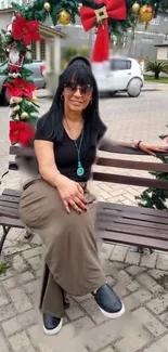 Woman sitting on holiday-decorated bench.