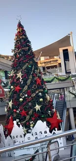 A towering Christmas tree decorated in an outdoor shopping area.