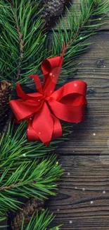 Festive wallpaper with pine branches and a red bow on wooden background.