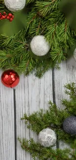 Festive pine branches with ornaments on rustic wood background.