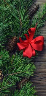 Festive mobile wallpaper with pine, red ribbon on wooden background.