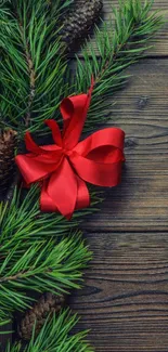 Festive pine branches with a red ribbon on wooden background.