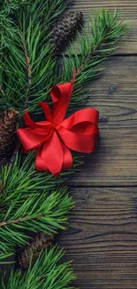 Festive pine branches with a red ribbon on wood.