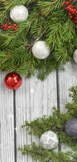 Festive wallpaper with pine branches, red berries, and ornaments on wooden background.