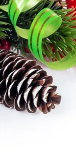 Festive pinecone with green ribbon and berries on a white background.