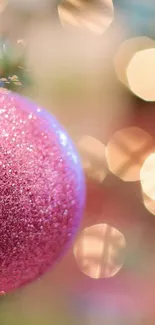 Pink Christmas ornament with festive bokeh lights on a holiday tree.