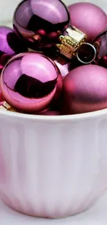 Pink Christmas ornaments in a white cup.