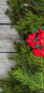 Festive mobile wallpaper with red poinsettias and green pine branches on wood.