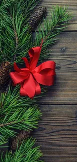 Red bow and pine branches on wood.