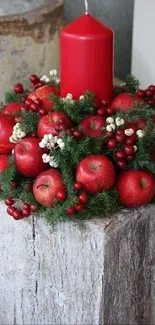 Red candle and apple arrangement on wooden block.