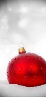 Red Christmas ornament on snowy background.