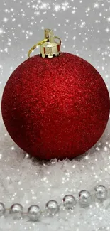 Festive red Christmas ornaments on snow with sparkling details.