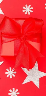 Festive red gift box with ribbon and stars in background.