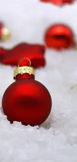 Festive wallpaper with red ornaments and glowing candles on snow.