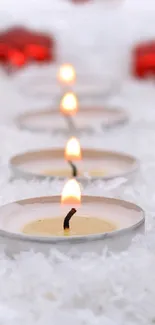 Red ornaments and candles on a snowy background for mobile wallpaper.