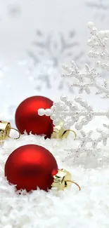 Christmas wallpaper with red ornaments and a snowflake on white snow.
