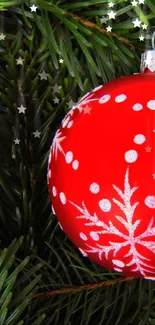 Red Christmas ornament among green pine branches wallpaper.