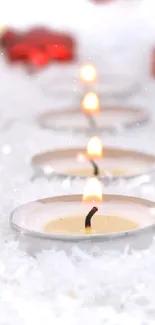 Red ornaments and candles on snowy background.