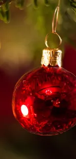 Red Christmas ornament hanging on a tree with festive lights.