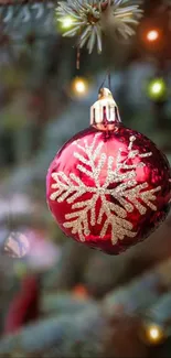 Red ornament with gold snowflake on a Christmas tree.