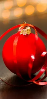 Red ornament with ribbon on a dark background, perfect for festive holiday themes.