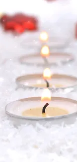 Red ornaments and candles on snow background.