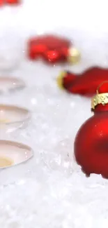 Red ornaments and candles on a snowy backdrop for a festive holiday feel.