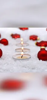 Red ornaments and candles on snowy background mobile wallpaper.