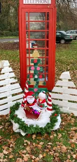 Red phone booth with festive Christmas decor and autumn leaves