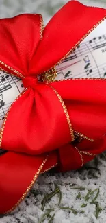 Red ribbon wrapped around sheet music on snow.